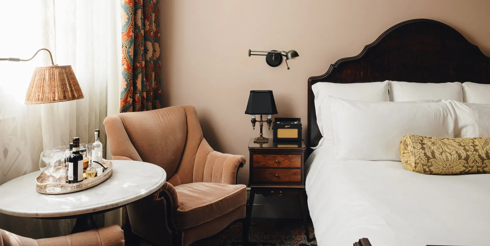 A Medium room: a walnut king bed, a peach armchair and a marble side table with a drinks tray