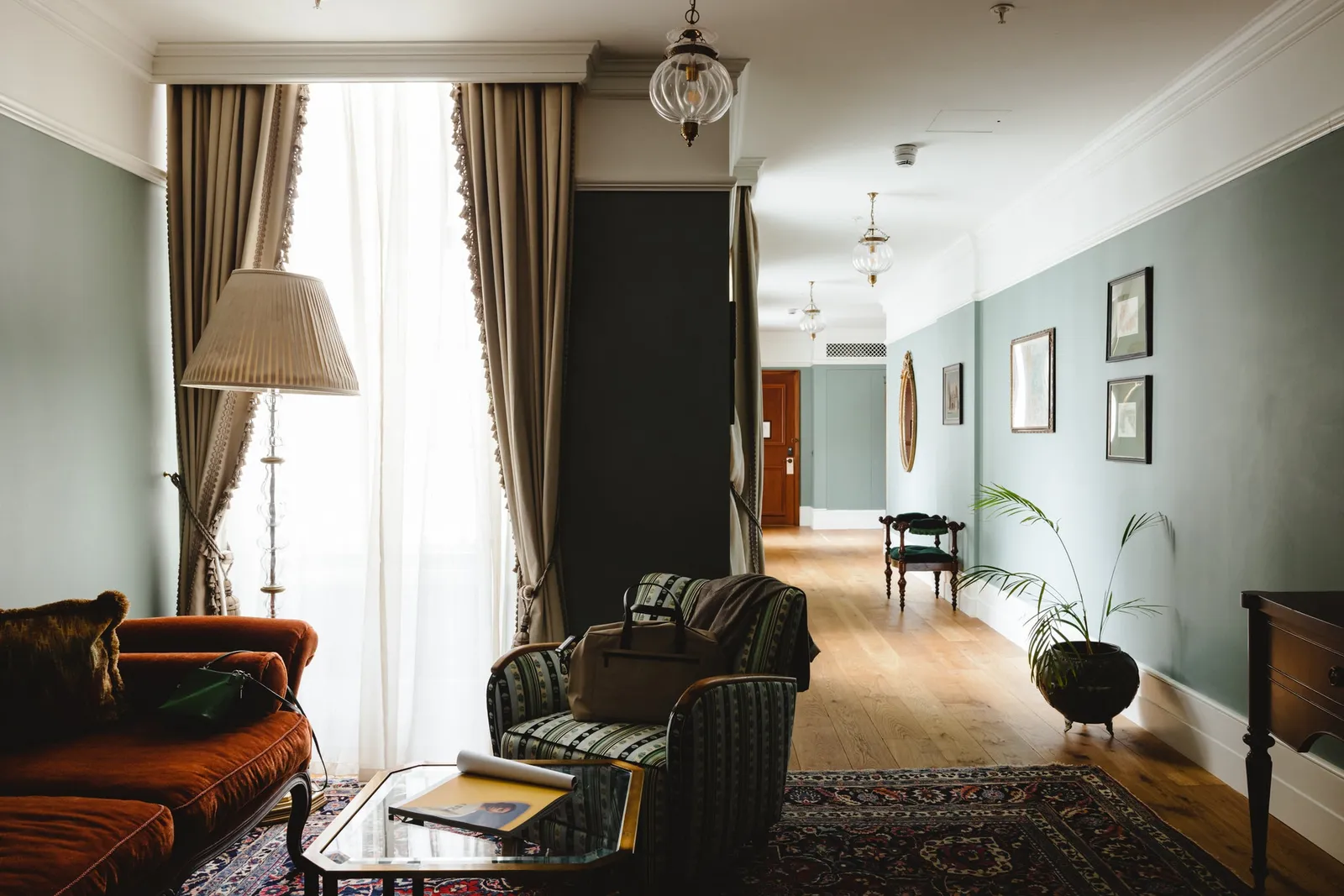 The Two Bed Family Suite: a pale green sitting room with armchairs, Persian rugs and a long corridor
