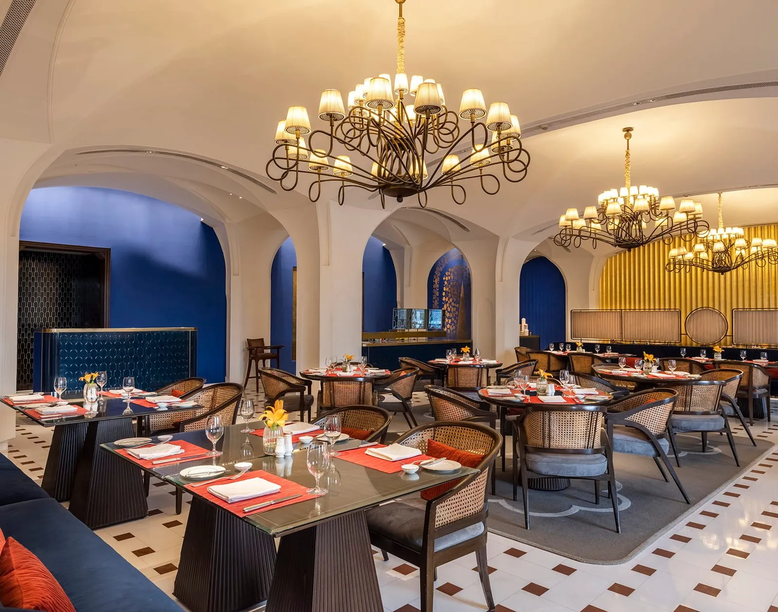 Bellevue’s dining room with iron chandeliers, blue walls and tables laid in red