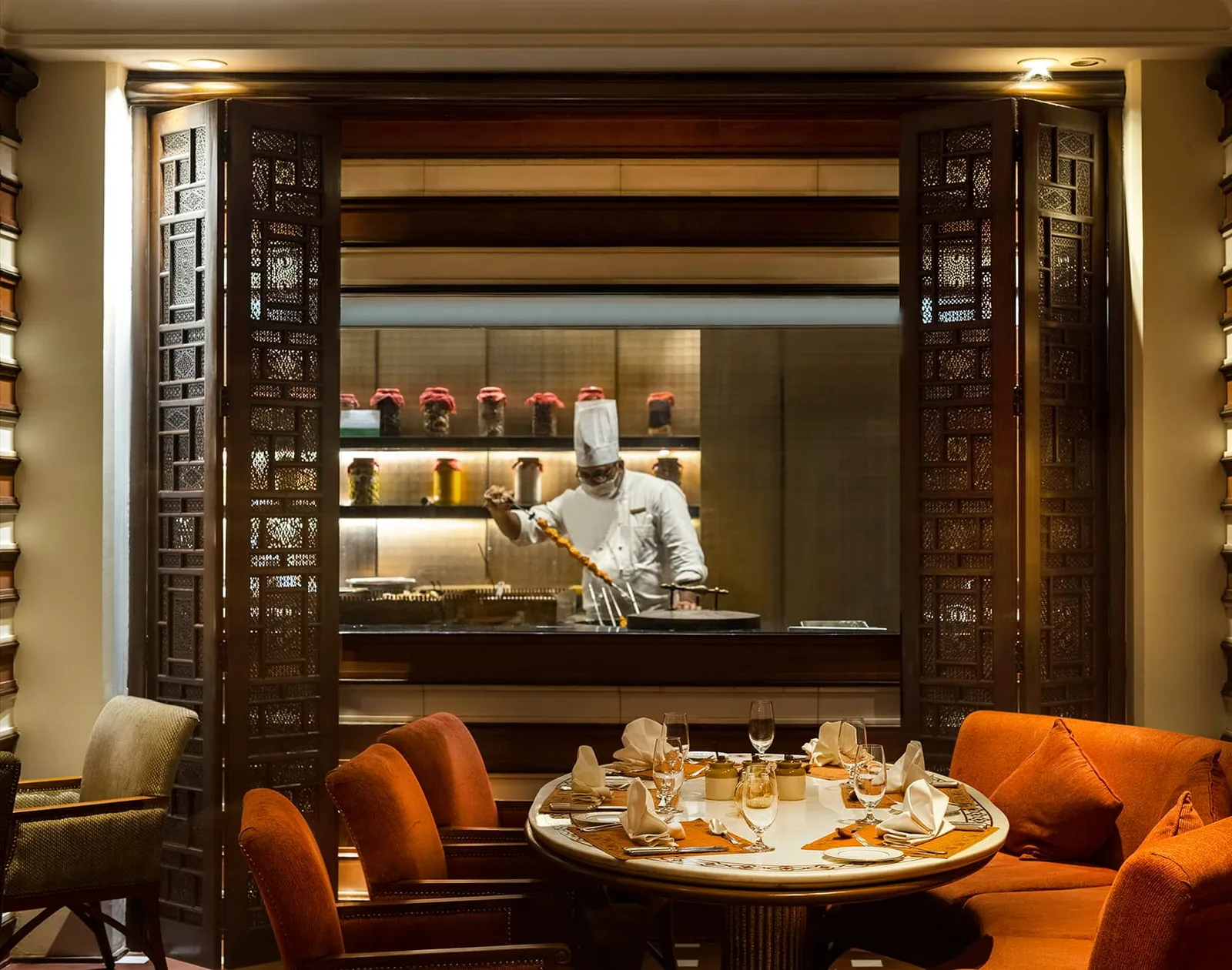 A cook at work behind Esphahan’s carved wooden screens, in front of a laid round table