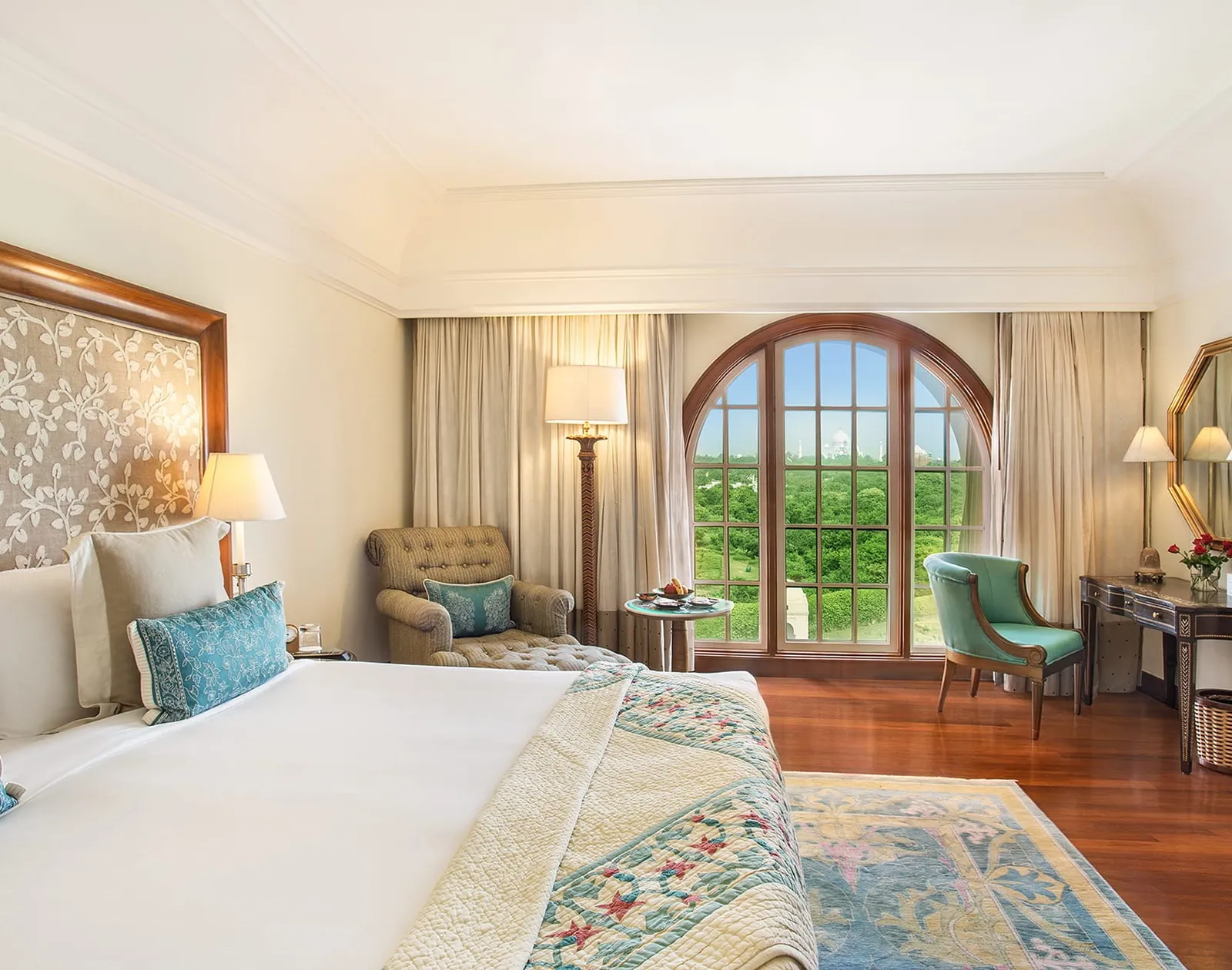 A Deluxe Suite’s bedroom with its king bed, an armchair and the arched window