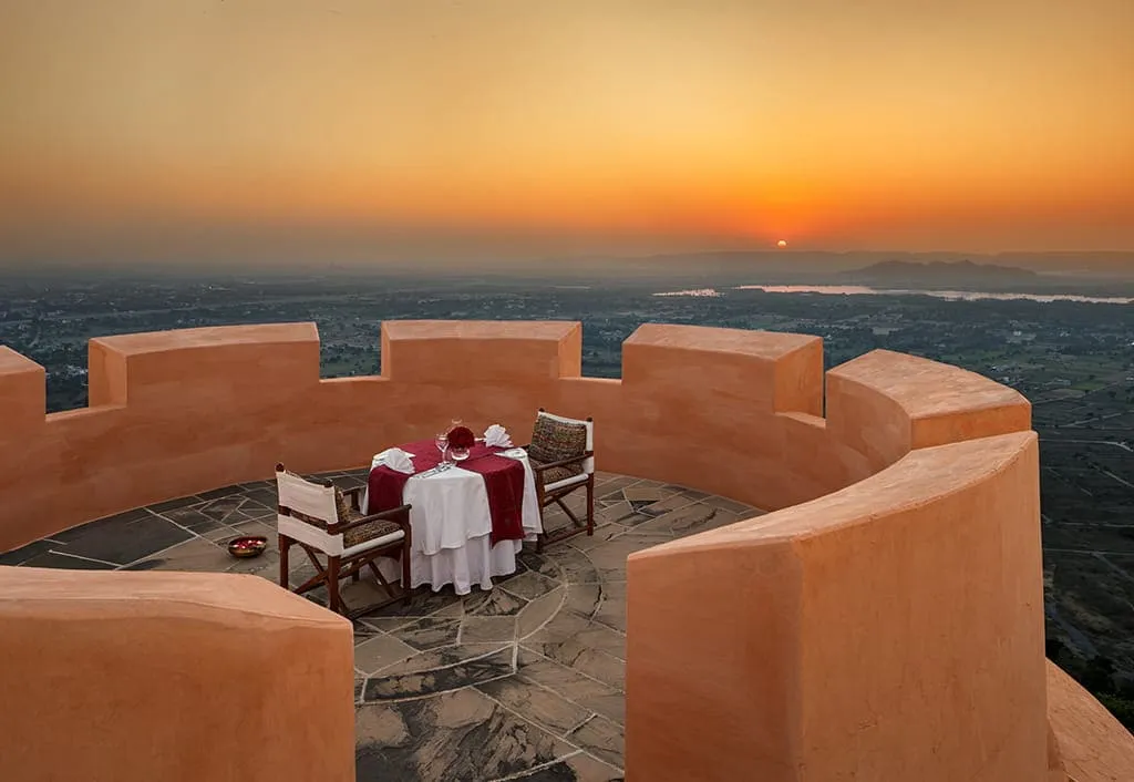 A table for 2 on Naila Fort’s pink ramparts, the sun setting over the hills