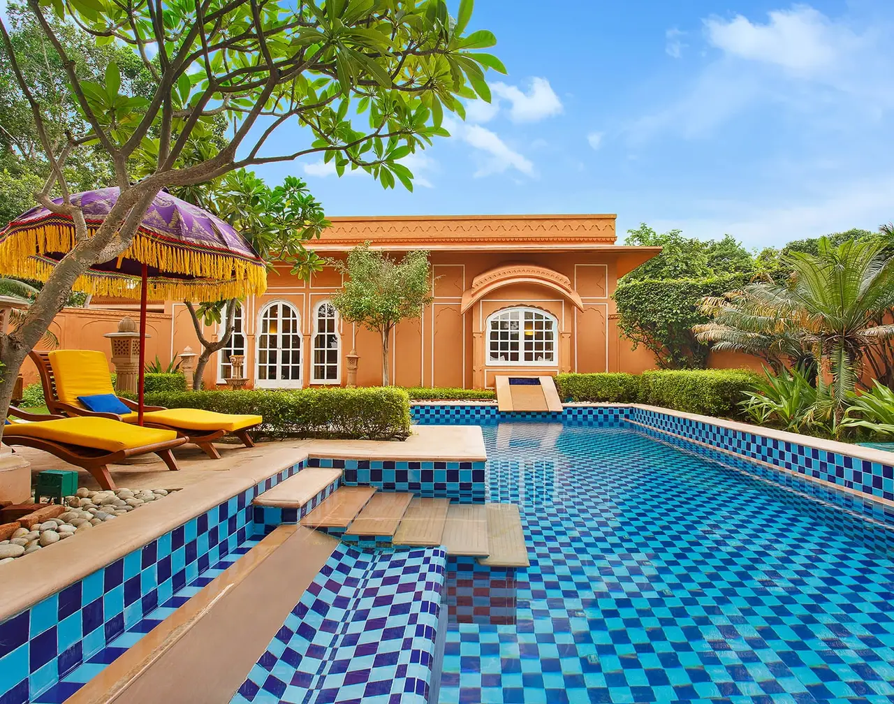 A Luxury Villa’s blue-chequered pool, with a parasol and the pink villa