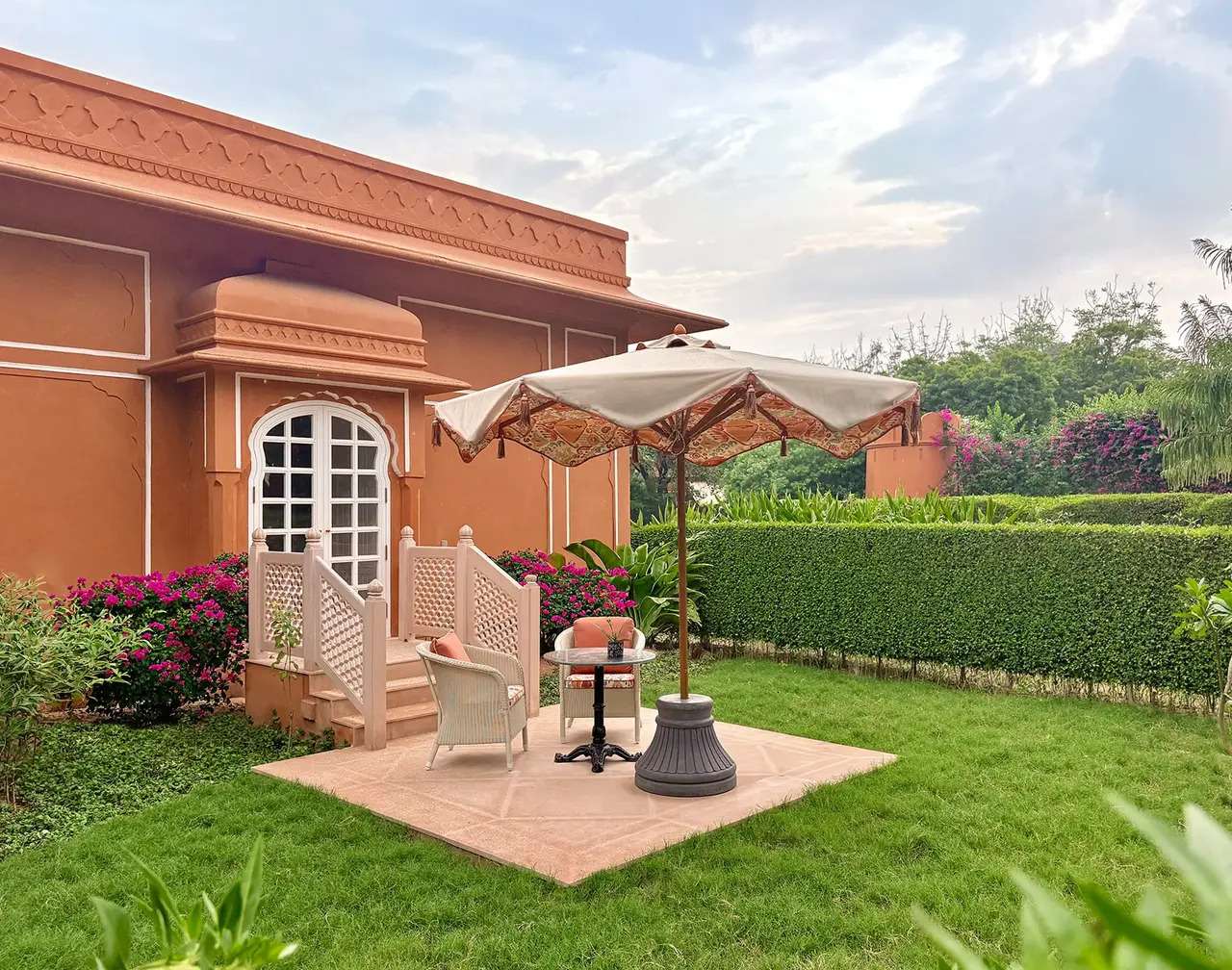 A Premier Room’s patio with a parasol, white chairs and a lawn