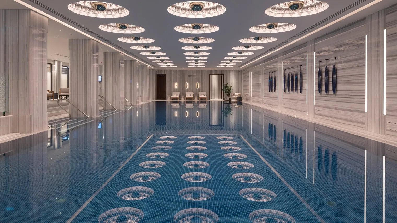 The indoor pool: the long basin with a mosaic floor, veined marble walls and a ceiling of lit domes in rows, mirrored in the water.