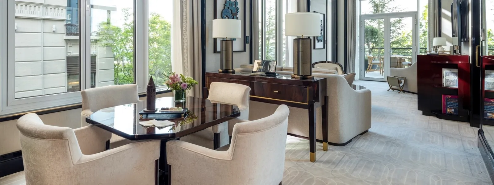 A Grand Bosphorus Suite with Balcony living room: a dark octagonal table with pale armchairs, the sofa with 2 lamps behind it and windows onto greenery.