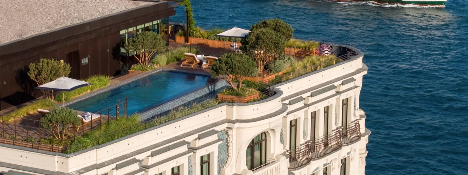 The Peninsula Suite’s roof from above: the private pool among trees and loungers, atop the pale façade, with the Bosphorus around it.