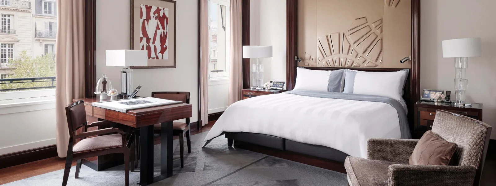 Deluxe Room with a double bed, table, armchair and windows facing Paris façades