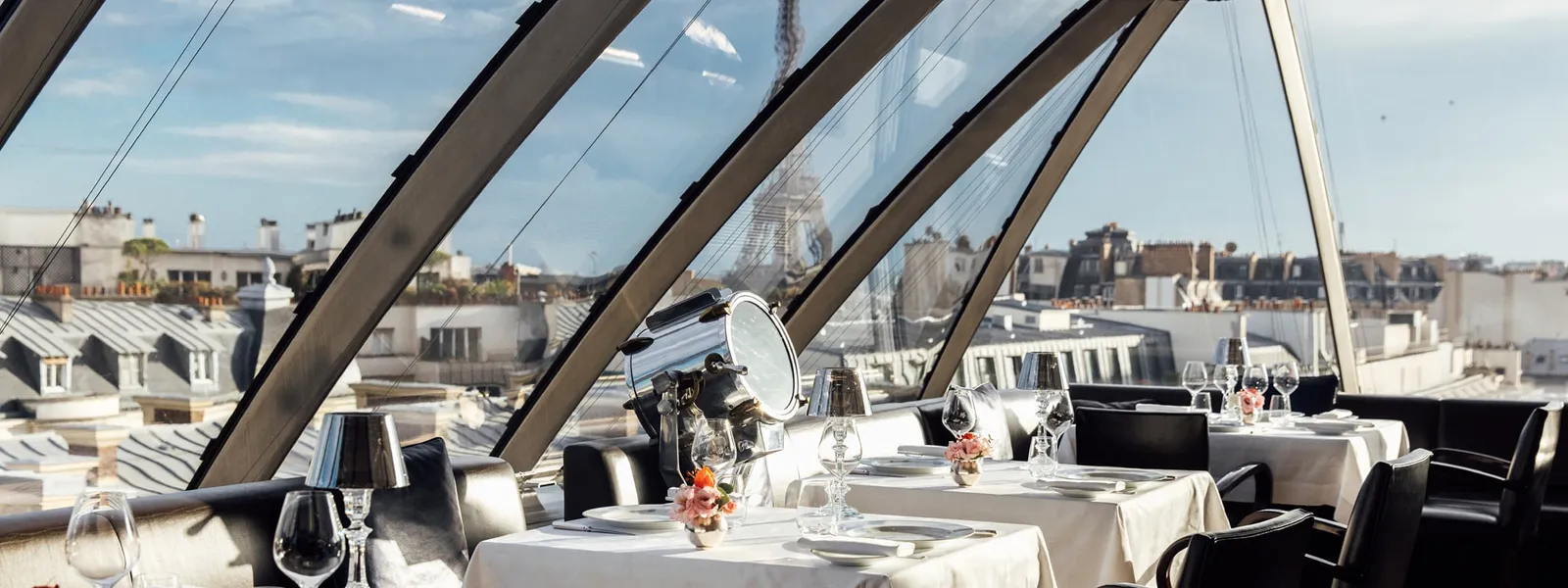 L’Oiseau Blanc beneath the sloping glass roof, with laid tables and rooftop views