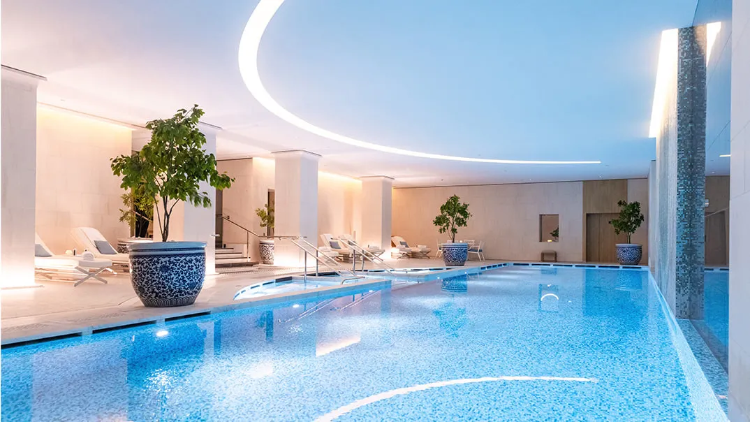 The indoor pool at The Peninsula Paris, with blue water and poolside loungers