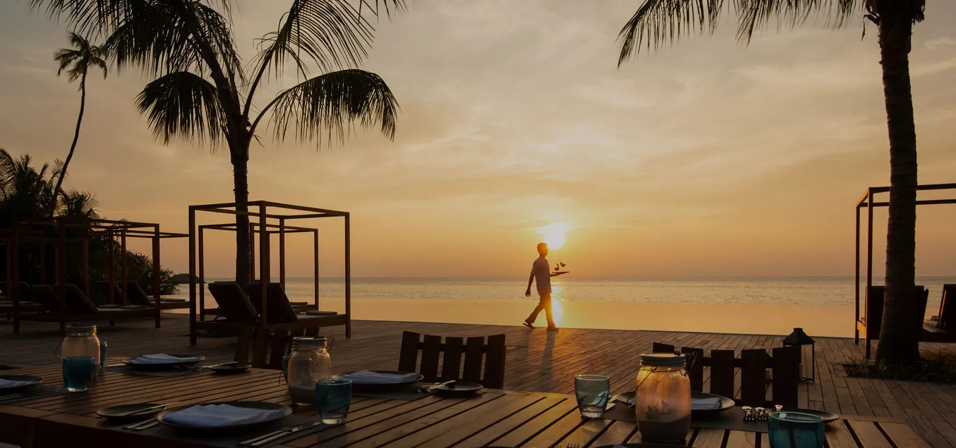Café del Sol’s seaside terrace at sunset, with tables and palms