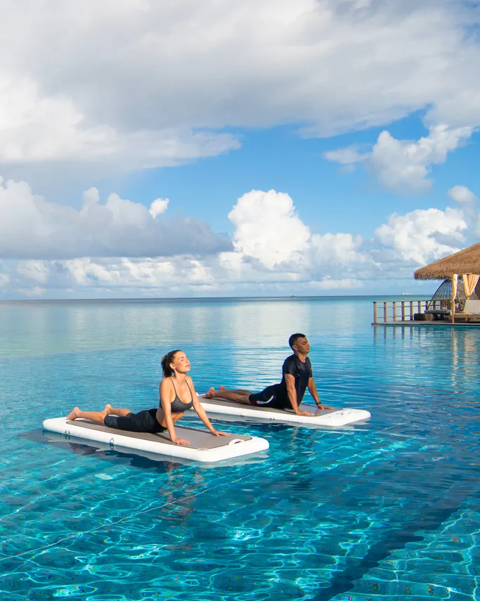 2 guests kneel on paddleboards in the calm lagoon