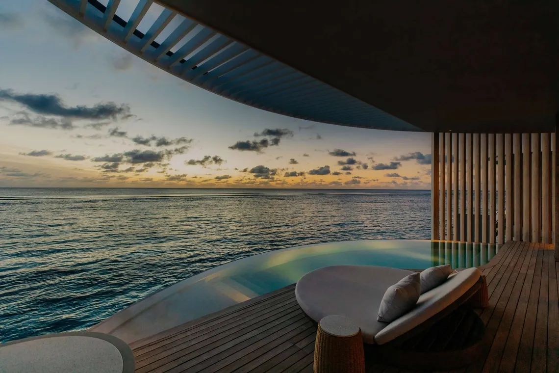 Wooden deck, curved pool and daybeds at the Ocean Pool Villa facing the sea