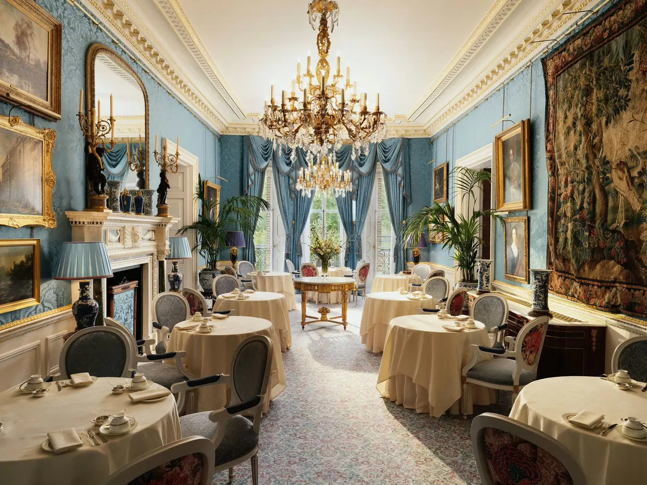 The Queen Elizabeth Room in William Kent House laid for tea: pale blue walls, gilded pictures and a crystal chandelier