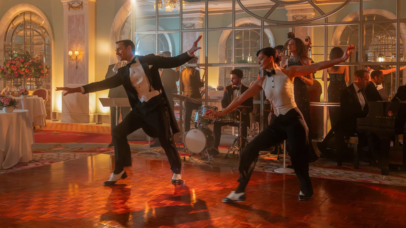 Live at the Ritz: 2 dancers in white tie dance between the restaurant tables, with the band behind