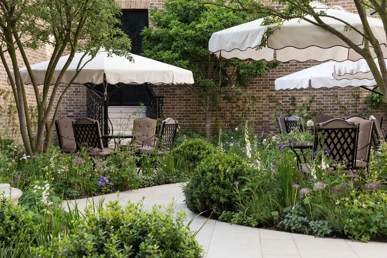 The Secret Garden: white parasols, tables among the planting and a brick wall