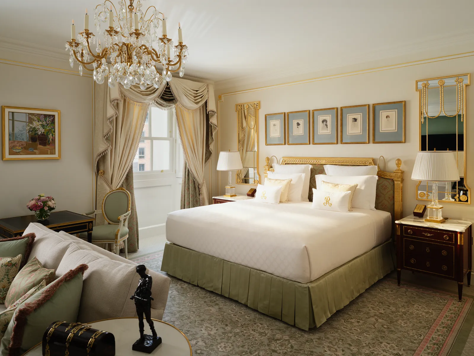 The Arlington Suite: a bed with an olive-green valance, a gilded chandelier, a sofa and a bronze statuette