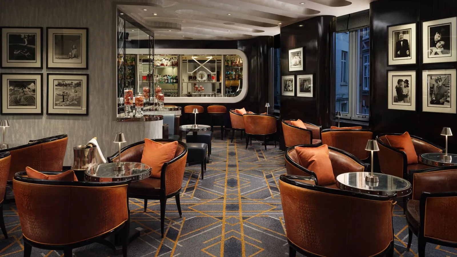 The American Bar: rust-coloured tub chairs, a geometric floor and black-and-white photographs on the walls