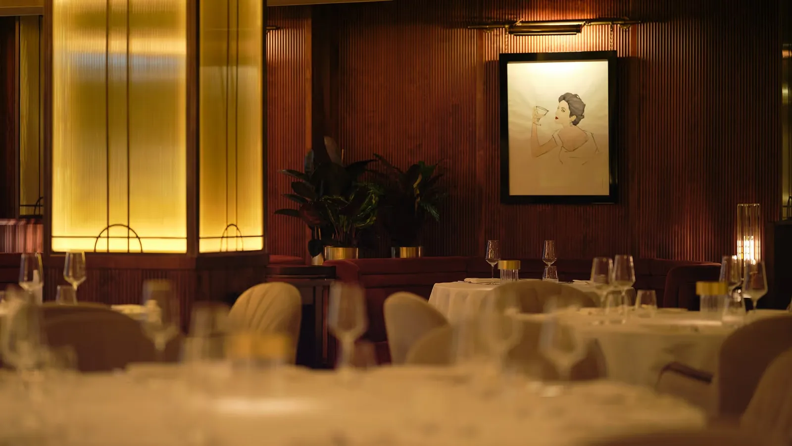 The Savoy Grill dining room, with wood panelling, gilded lamps and laid tables