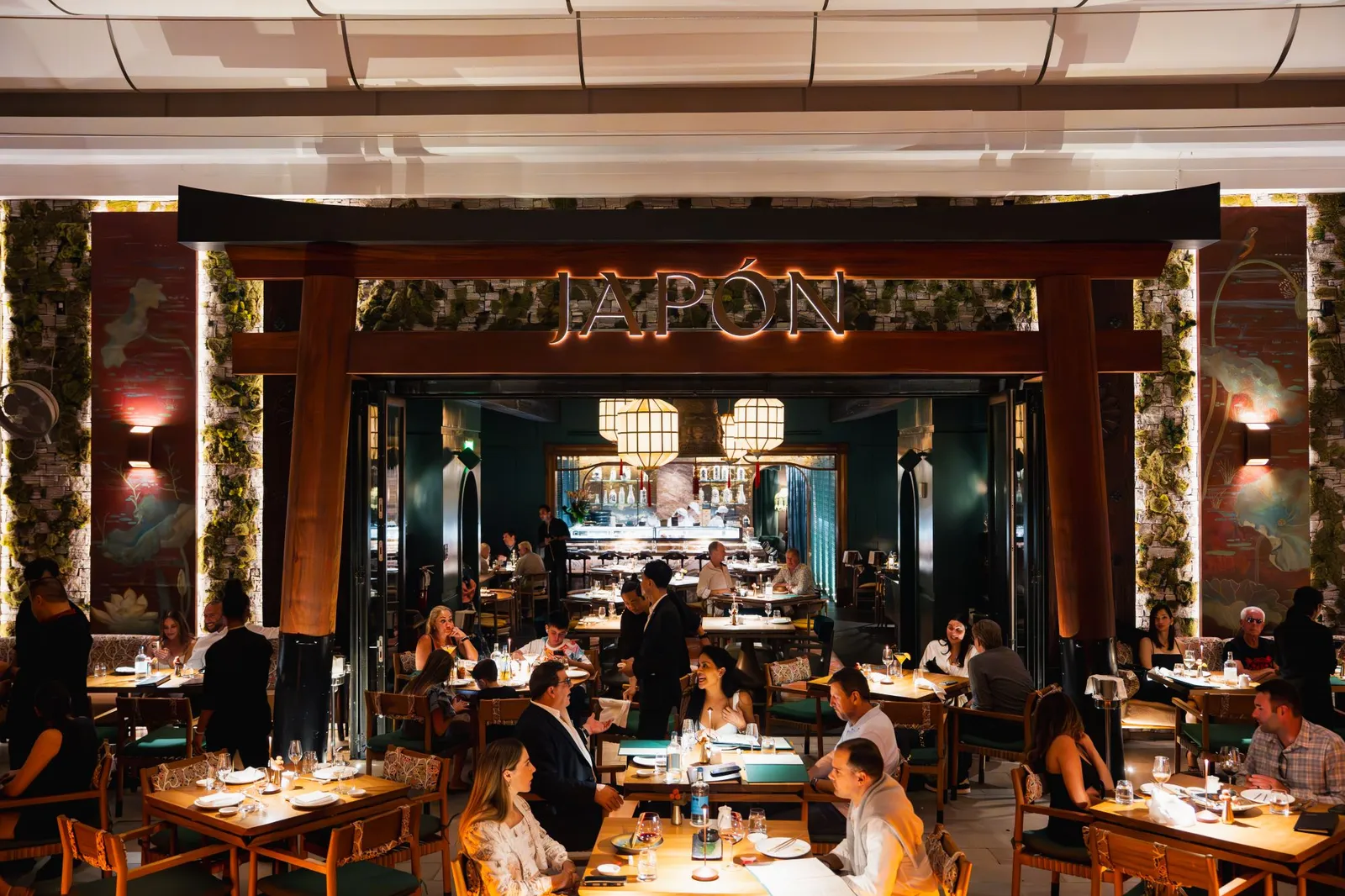 The entrance to Japón, a timber gate with its lit sign, and full tables in the dining room and the courtyard.