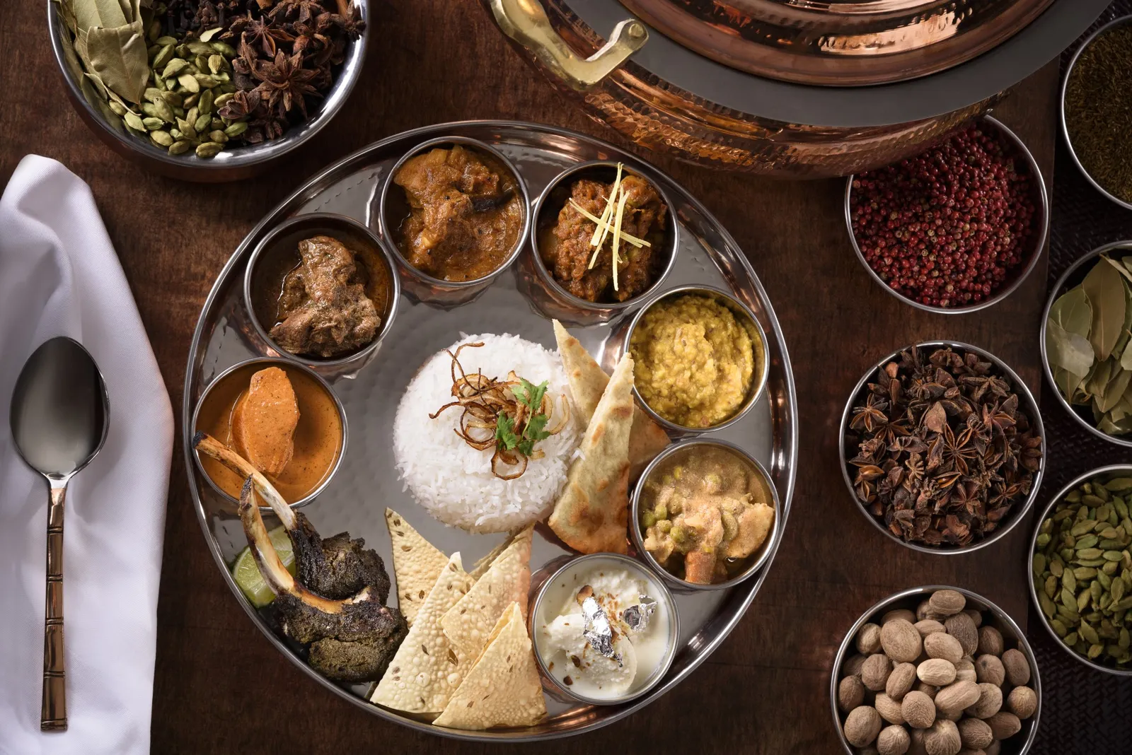An Indian thali at Jaya from above: rice, curries and bread in metal bowls, among dishes of spices.
