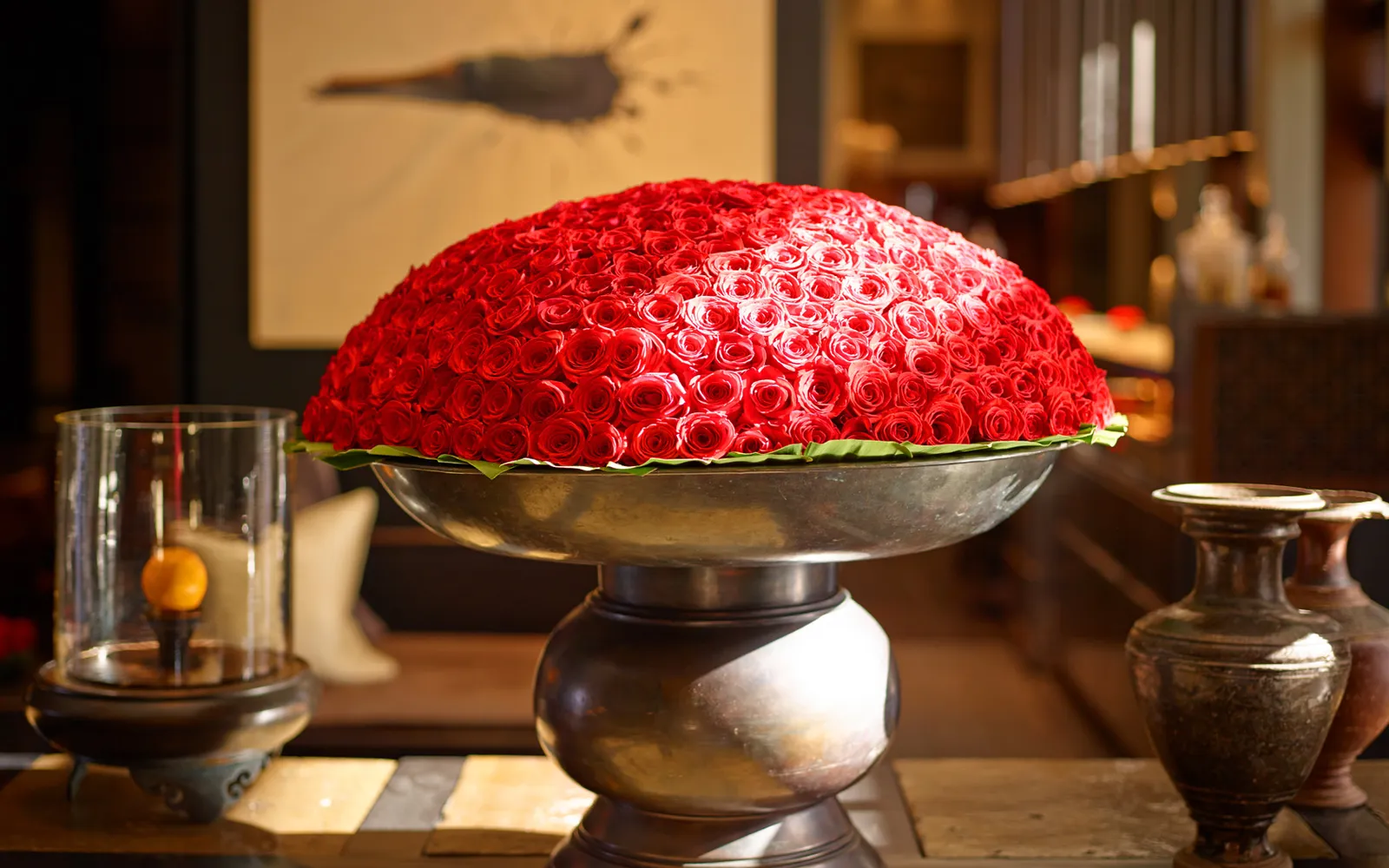 The dome of red roses at the centre of the lobby, on a large metal urn, among candles and antique jars.