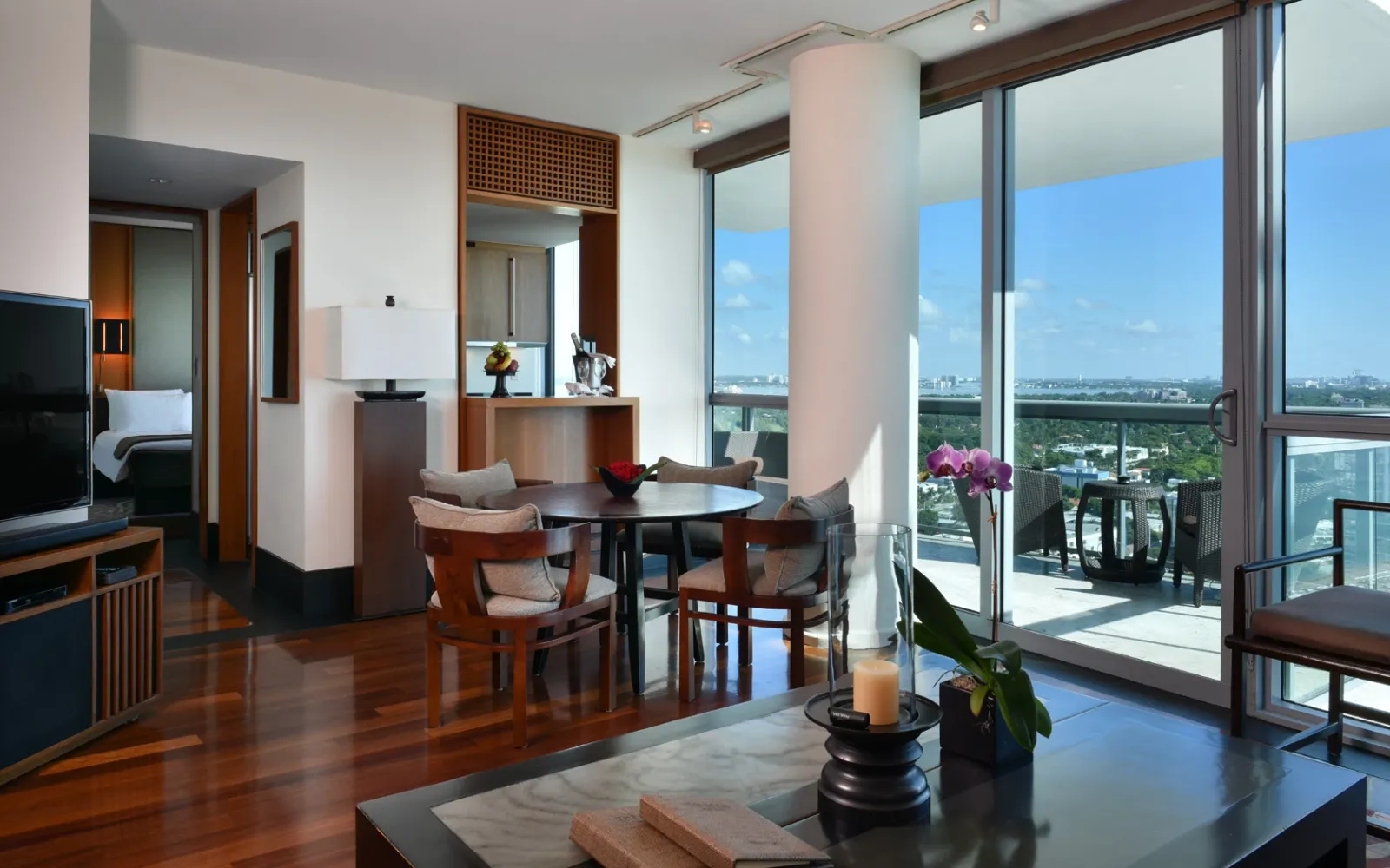 A One Bedroom Ocean Suite’s living room, with a round table, floor-to-ceiling windows and the balcony.