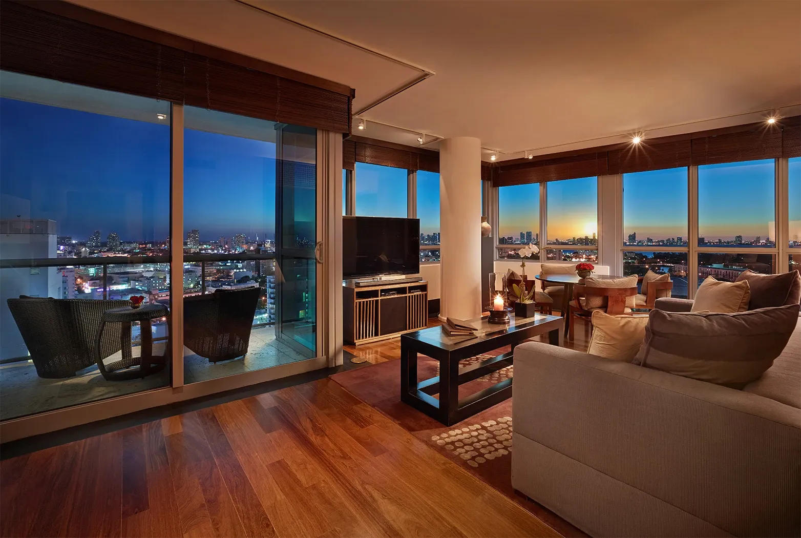 The living room of a multi-bedroom Ocean Suite at dusk, with its balcony and Miami Beach’s lights beyond the glass.