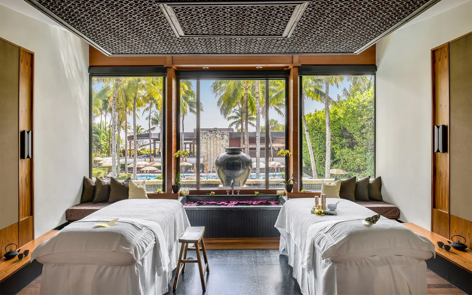 A spa suite with 2 treatment beds, a petal-strewn bath and 3 windows onto the palms and the pools.