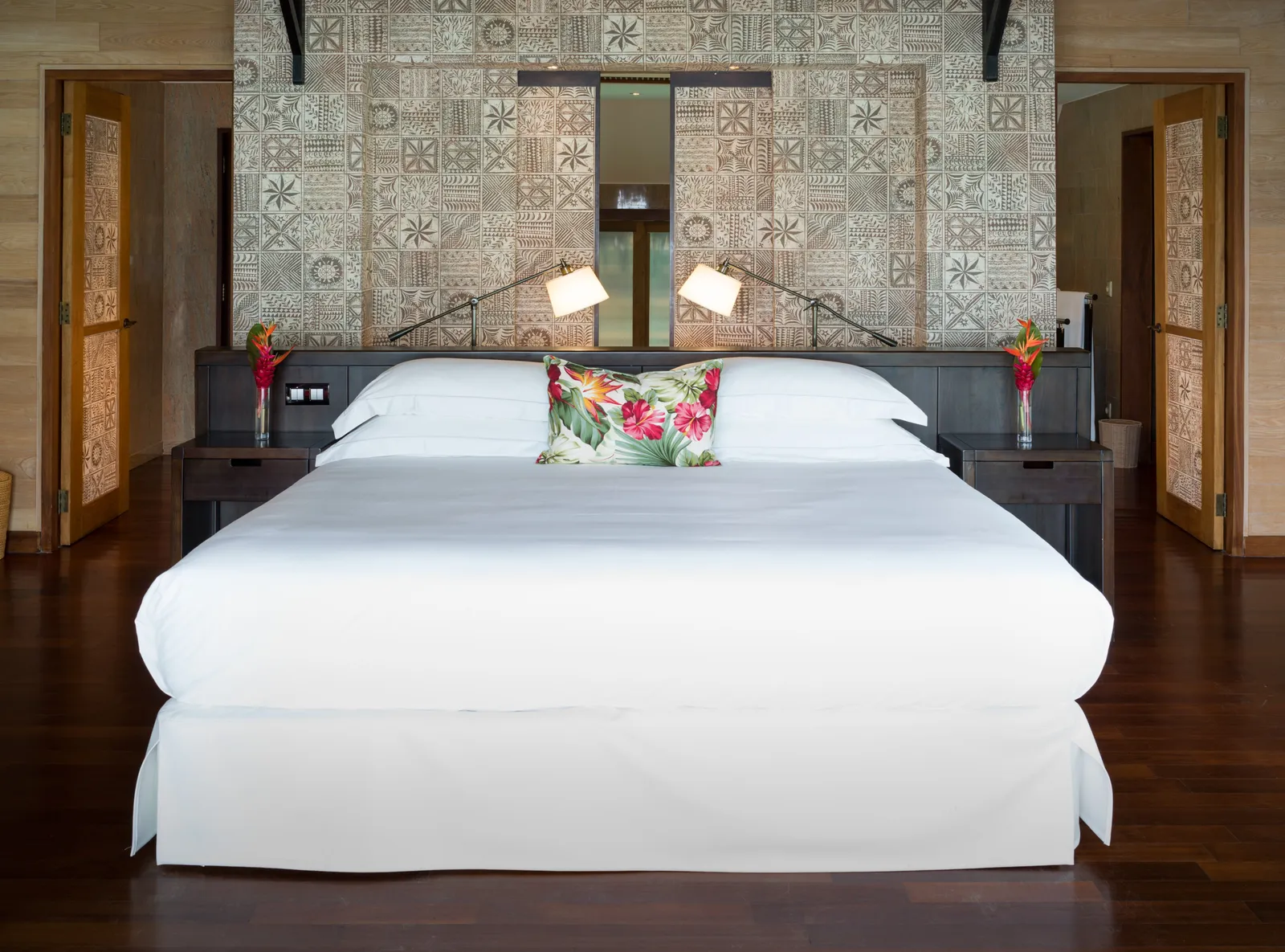 A king bed under a timber ceiling, the lagoon beyond the windows