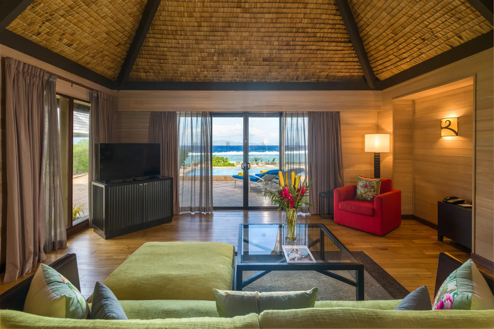 A garden villa’s sitting room, its doors open on the pool