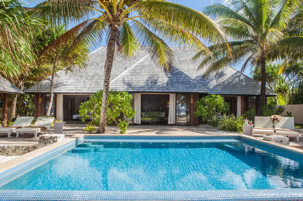 A villa’s private pool in front of the house, under the palms