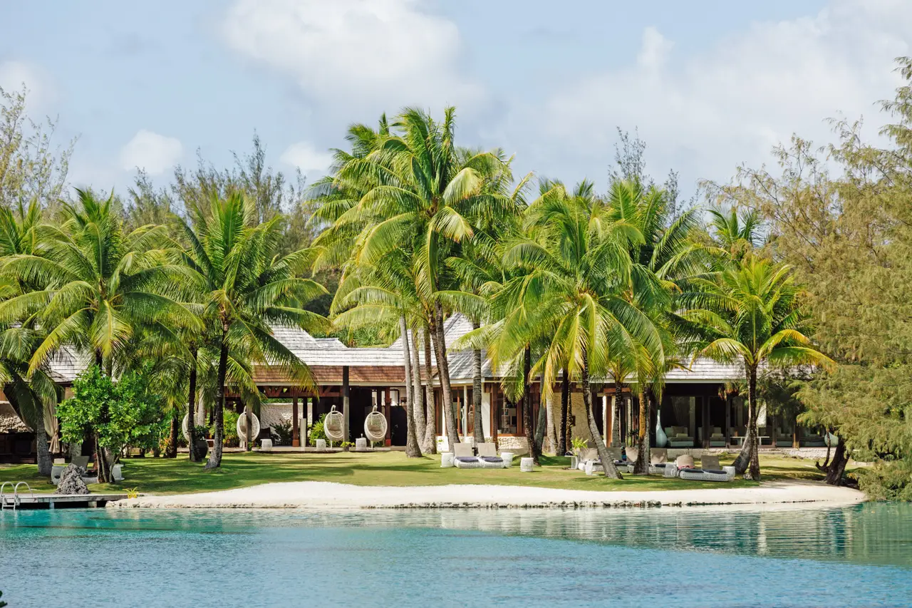 The spa’s islet across the water: palms, a strip of sand and low pavilions