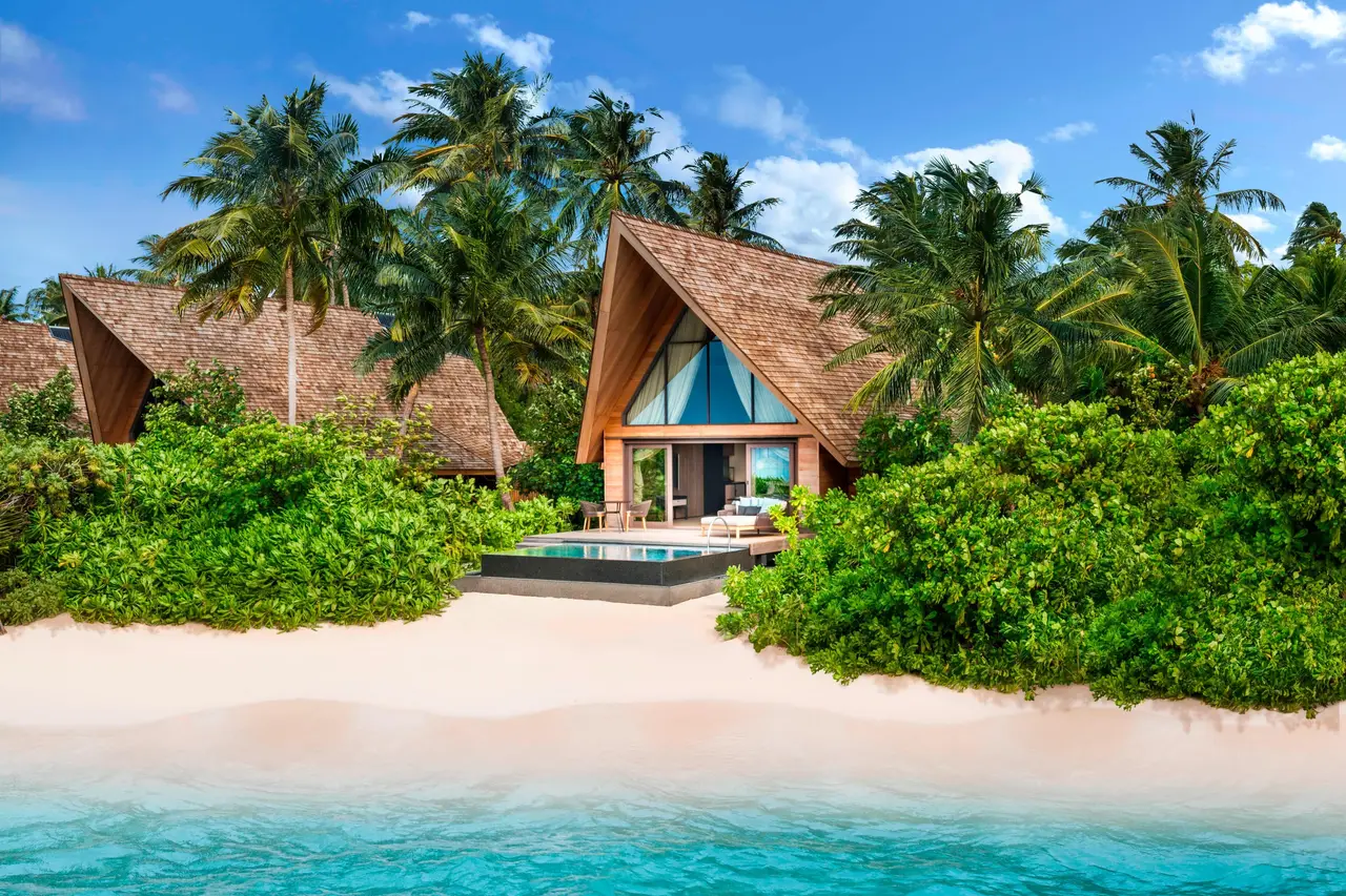 A Beach Villa on white sand among the palms, its pool in front