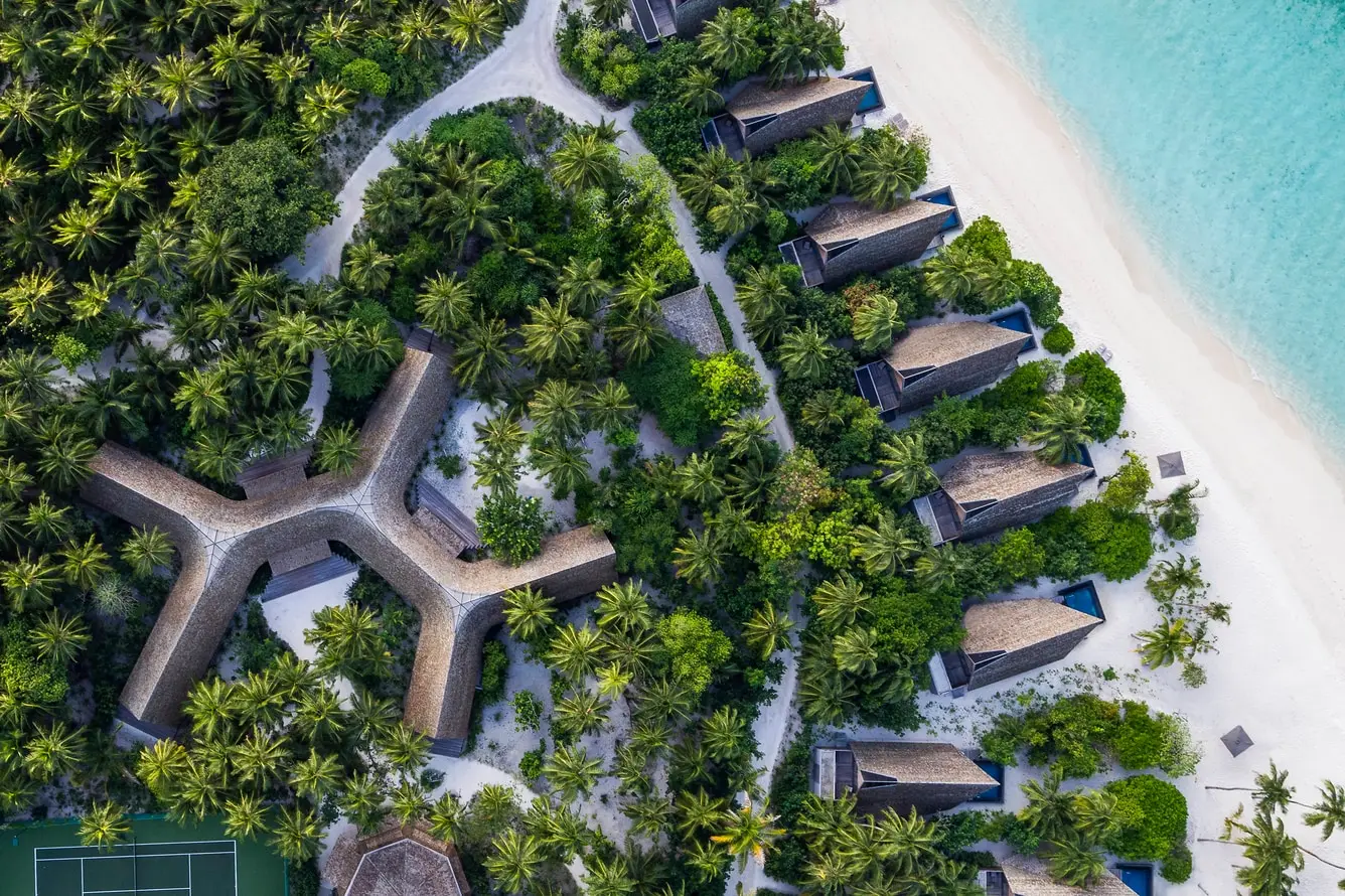 The island from above: Vommuli House among the palms, the tennis court and the beach villas