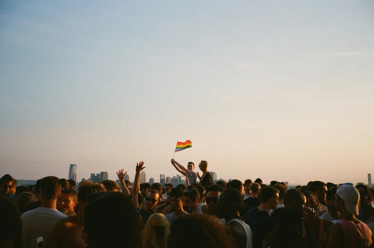 The crowd on Le Bain’s roof at sunset, a rainbow flag and the distant towers