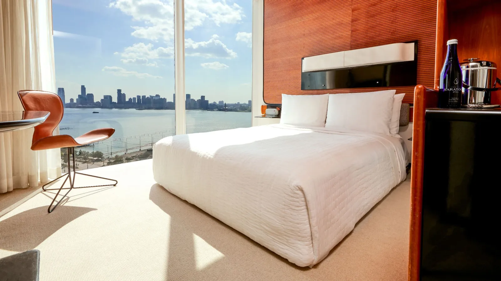 A Deluxe Queen with the bed facing the river and an orange chair