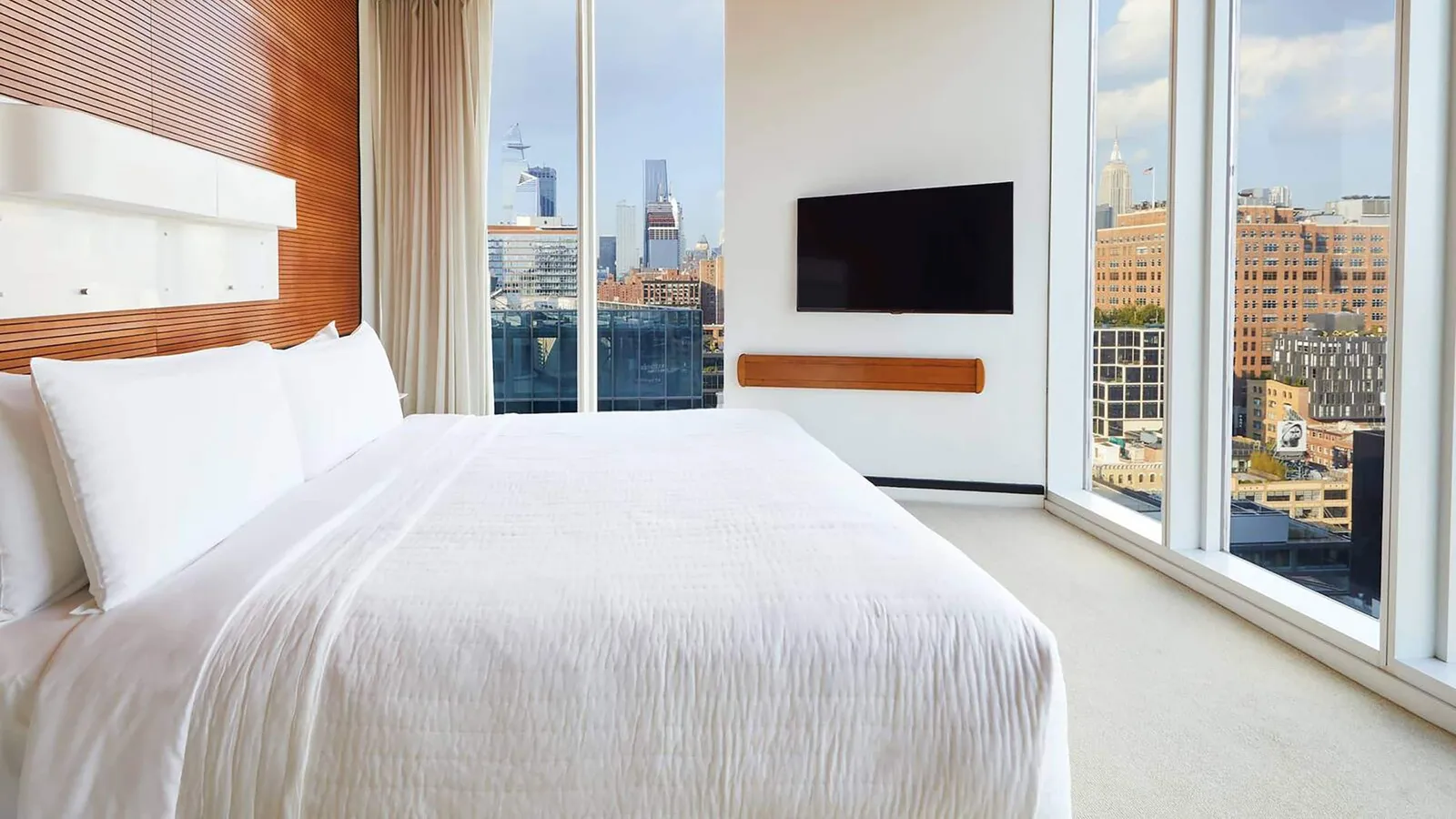 An Empire Corner King, the white bed between 2 glass walls over Chelsea’s roofs