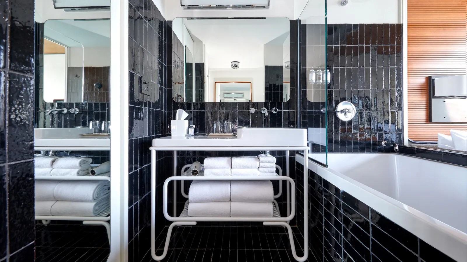 The black-tiled bathroom with its white basin and the tub