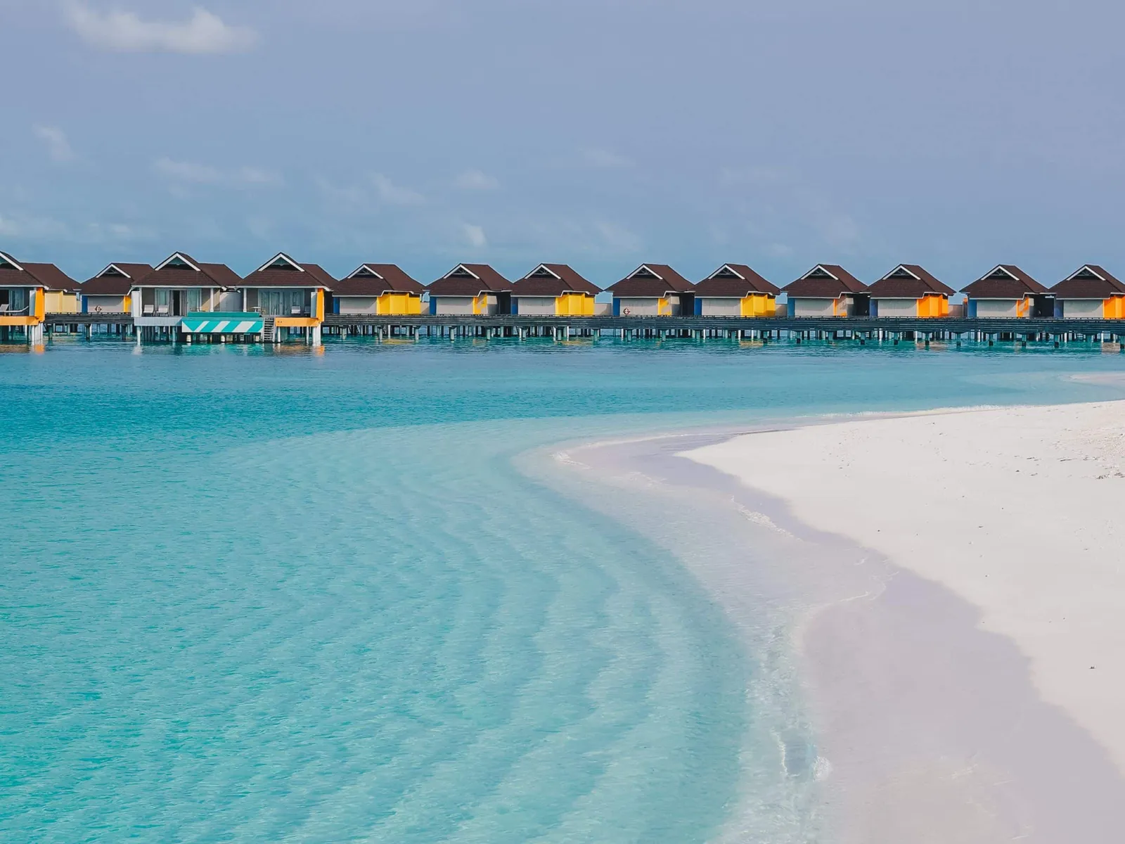 The white sandbank running into the pale lagoon, with the line of water villas on the horizon.
