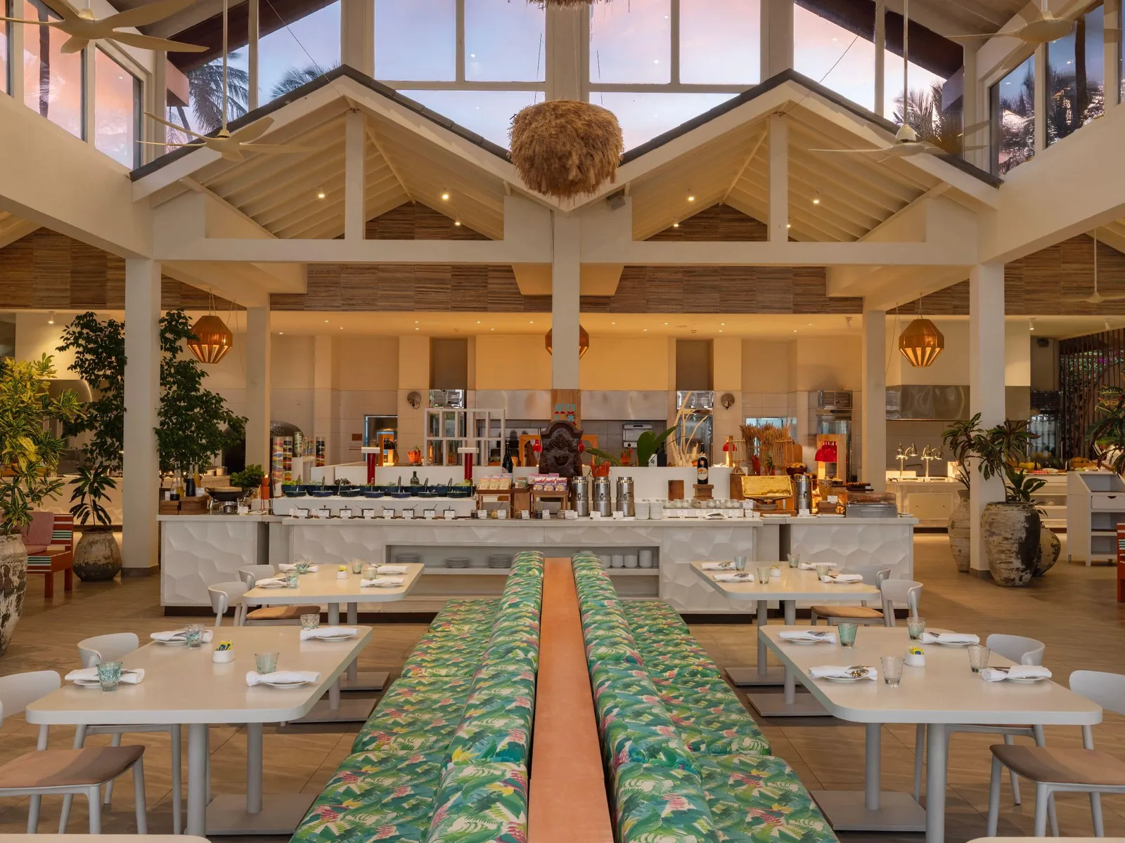Kula’s dining room, the buffet at the back, white tables and the long leaf-print bench under the pitched roof.