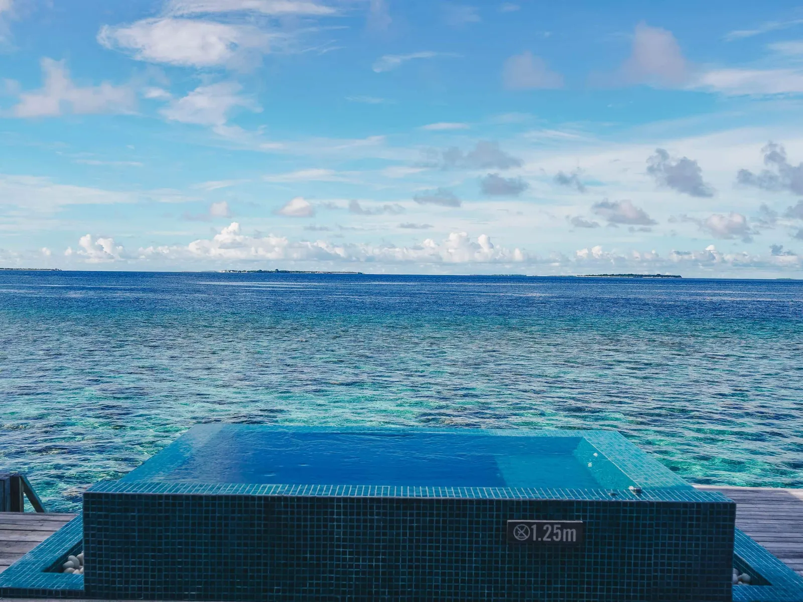 An Ocean Overwater Villa’s infinity pool merging into the open ocean.