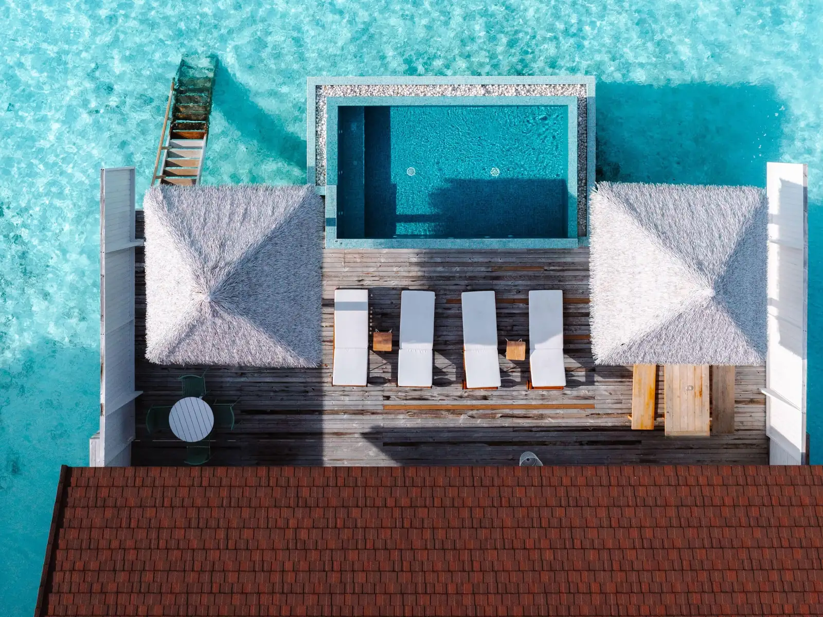 The 2-bedroom water villa from above: the 2 thatched roofs on either side, the pool and the loungers on the deck.