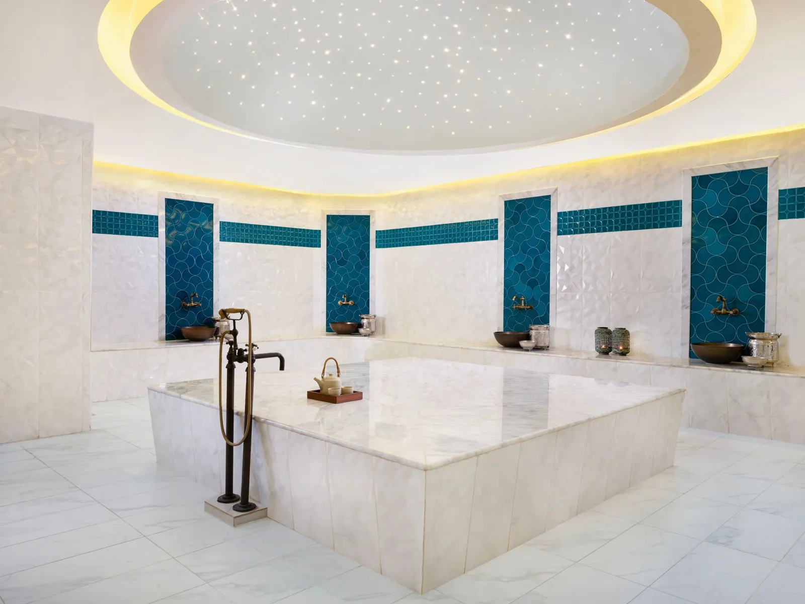 The spa’s hammam: the white marble platform, the wall basins between blue tiles and the starry ceiling.