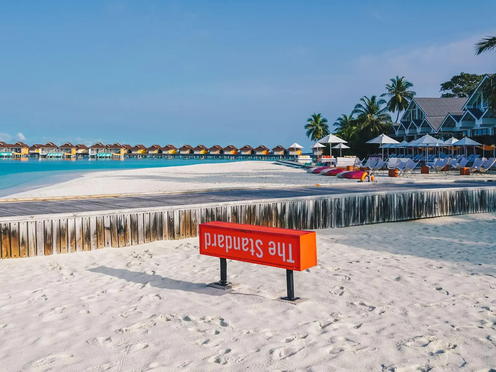The Standard’s red sign, its name upside down, planted in the sand before the beach and the water villas.