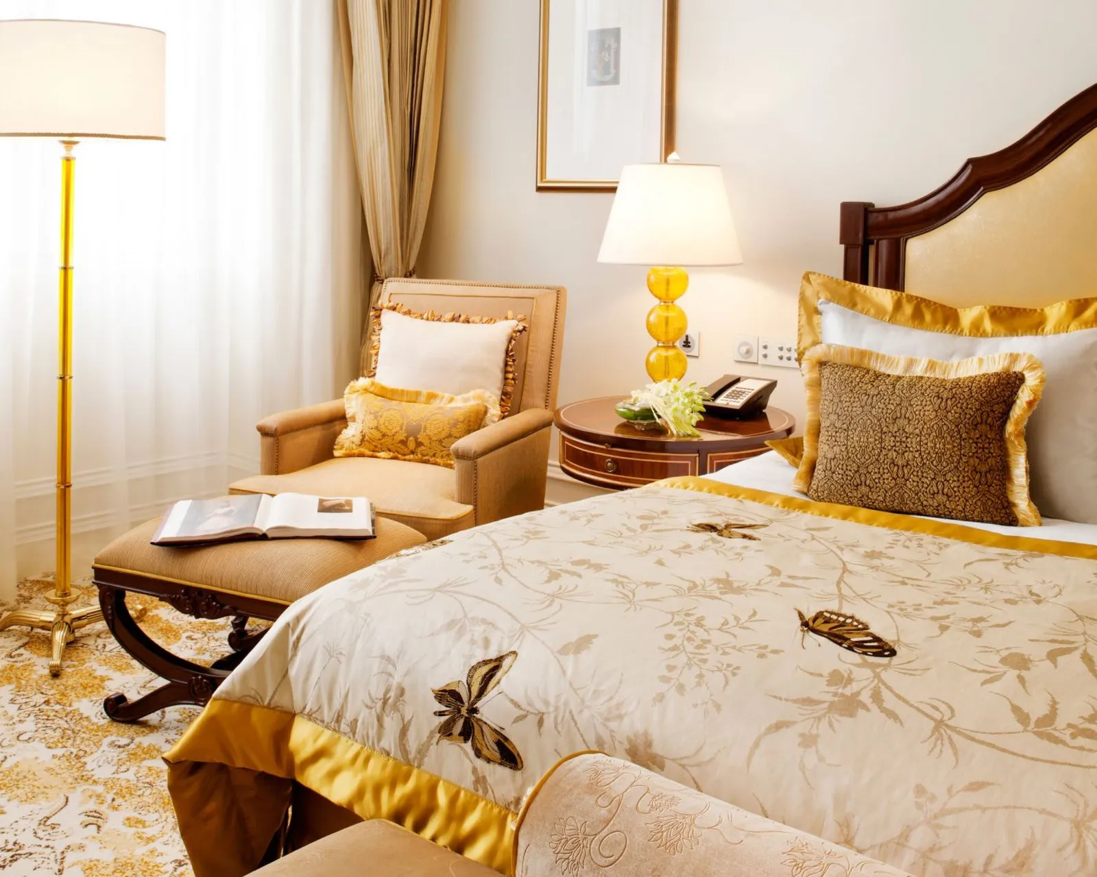 Una Executive Suite con letto dorato, poltrona e lampada gialla