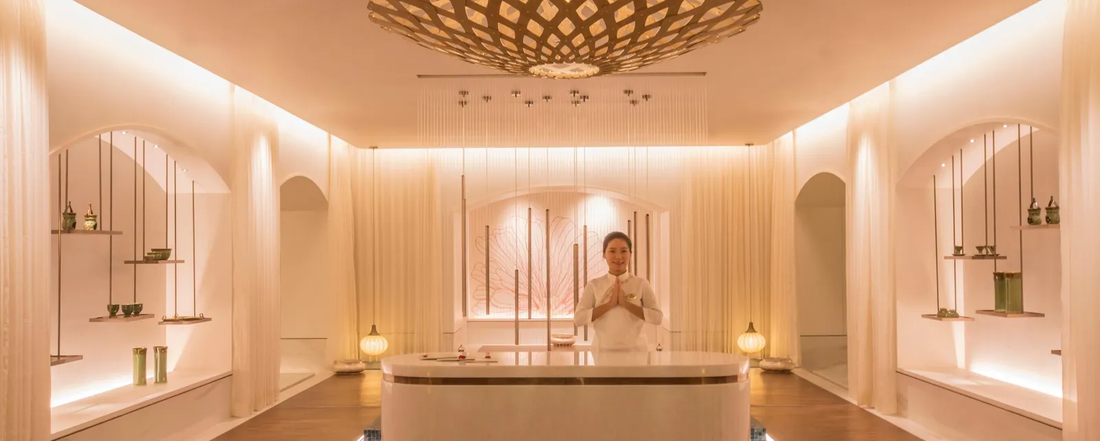 L’accoglienza della spa J Wellness Circle, con pareti chiare e un lampadario a petali