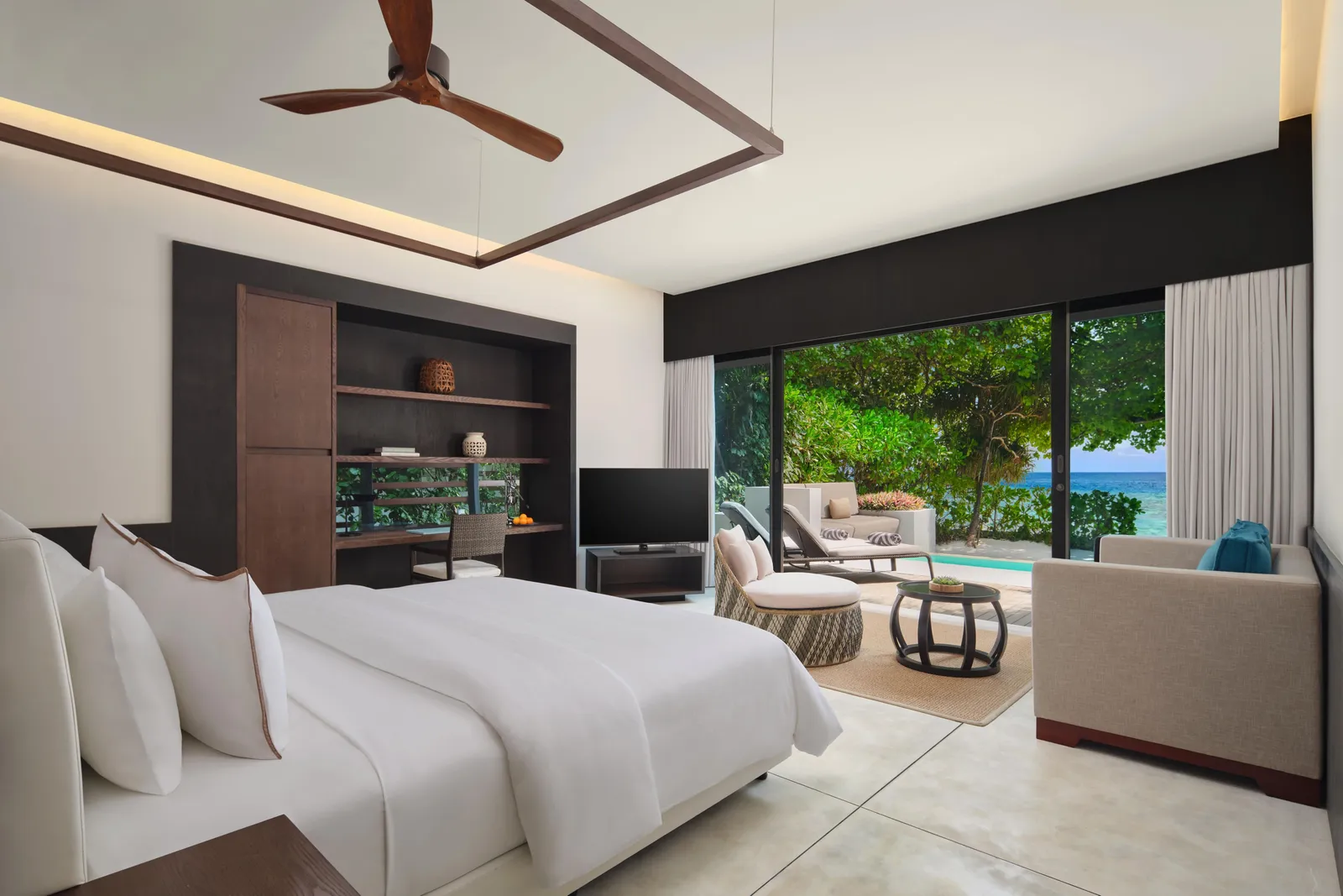 A Beach Villa – Pool bedroom: the king bed, the sitting area and the glass on the garden, with the pool and the sea beyond.