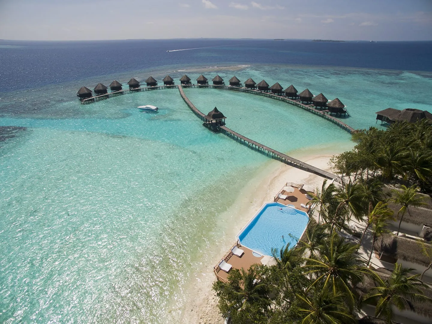 The pool beside the beach from above, with the jetty and the row of water bungalows in the lagoon.
