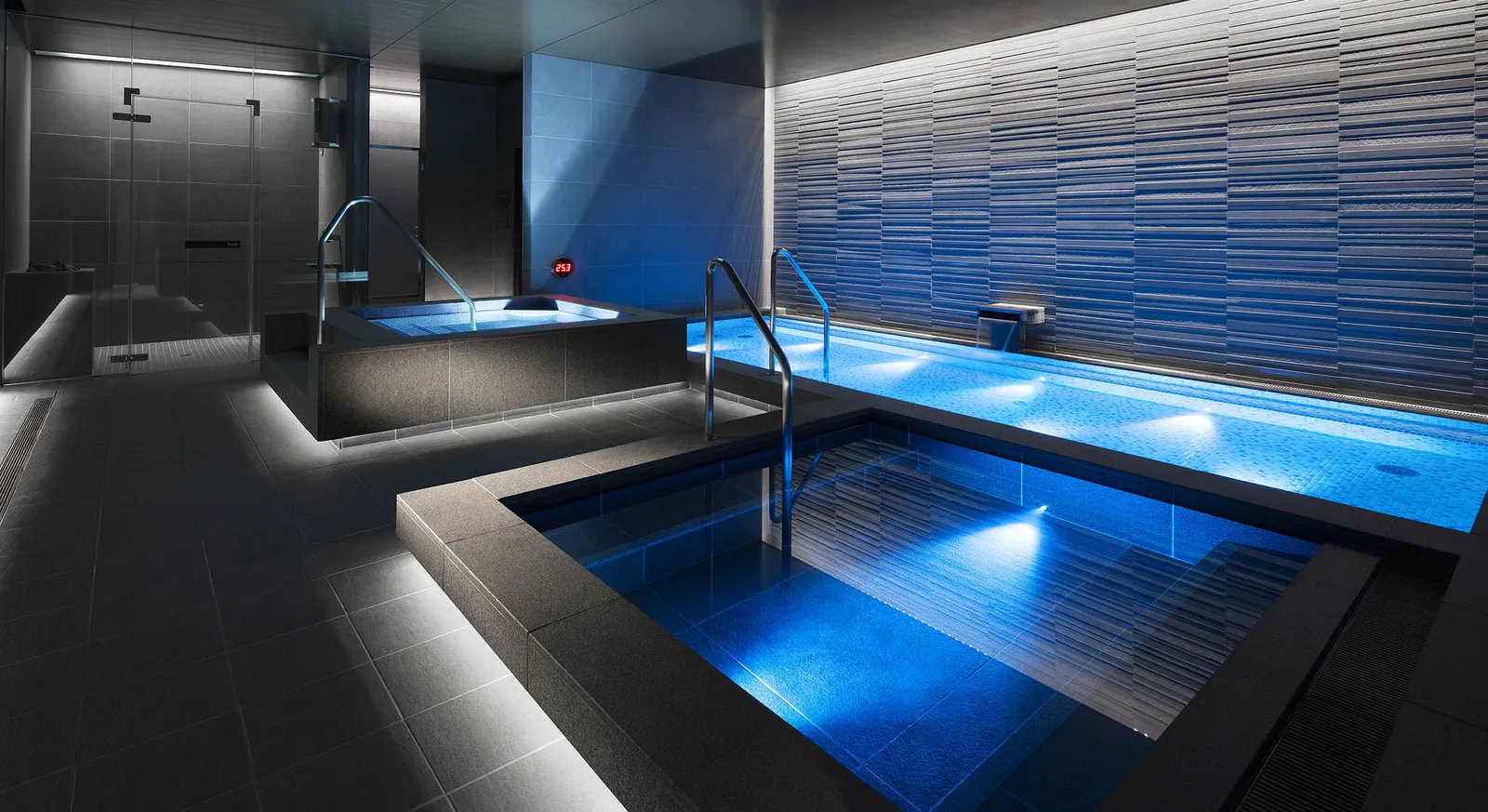 Bath & Relaxing: 2 blue-lit baths, the striped tile wall and the showers at the back.